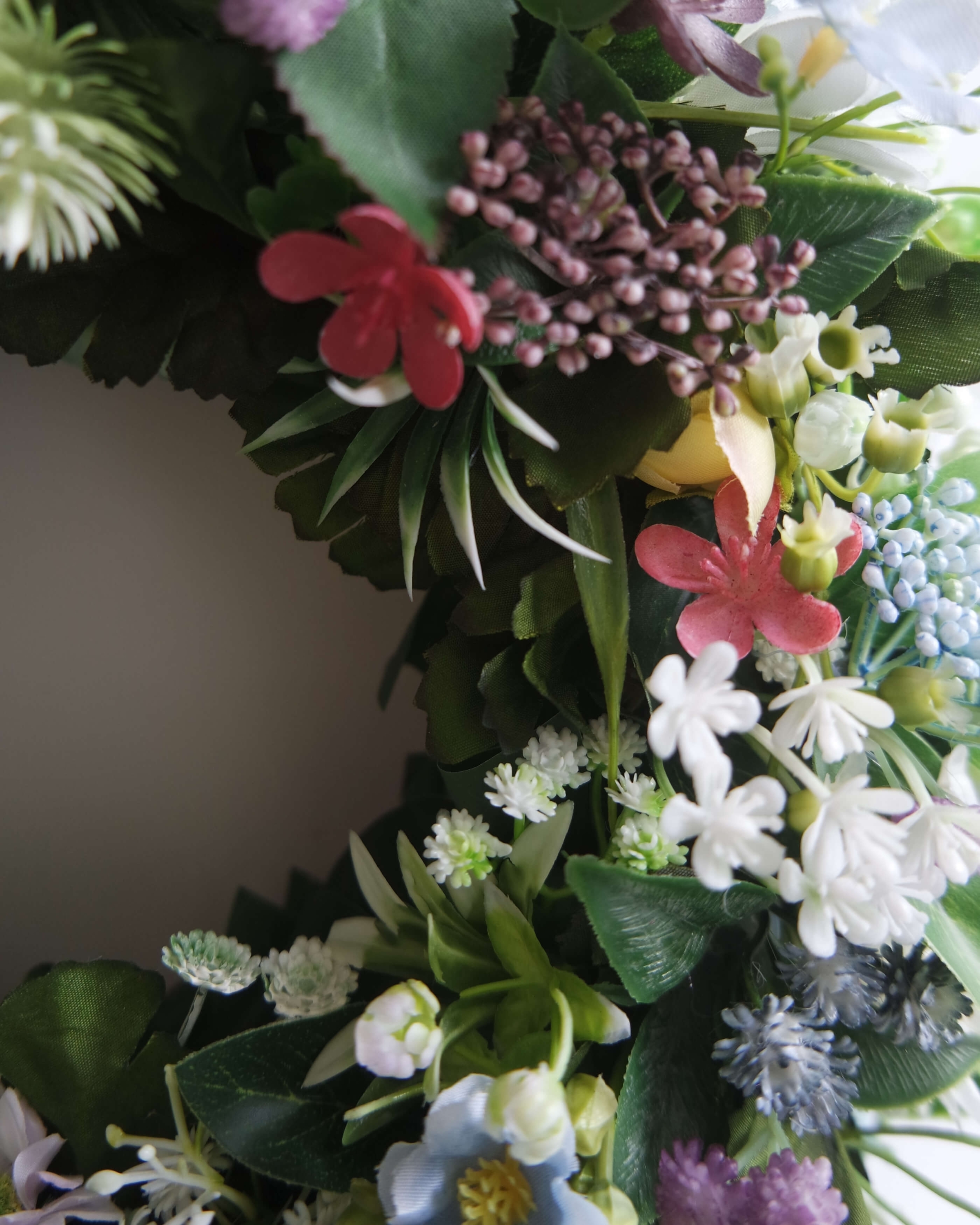 Zbliżenie drugie na sztuczny zielony wianek Ogród marzeń z kwiatów – dekoracja na drzwi